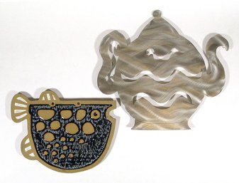TWO DECORATIVE TRIVETS, INCLUDING GLAZED STONEWARE AND LASER-CUT STAINLESS STEEL