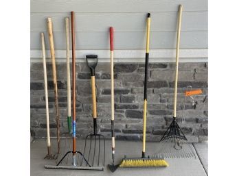 Assorted Collection Of Yard Tools Including Pitch Forks, Rake, Walking Stick, Hoe, And More