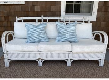 Vintage Rattan Sofa In Distressed White With Pair Of Contrast Throw Pillows In White And Blue