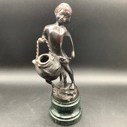 Metal Statue Of Child Carrying A Water Vessel On A Marble Base With Bronzed Patina