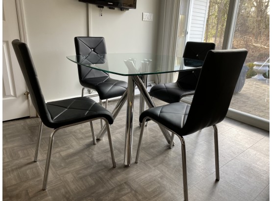 Modern Glass Top Table With Chrome Legs And Four Black Chairs