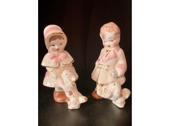 Two Small Figurines Dressed In White With Their Dogs