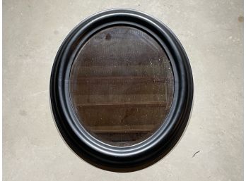 An Oval Mirror In Black Wood Frame