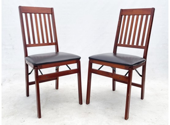 A Pair Of Folding Chairs With Vinyl Seats