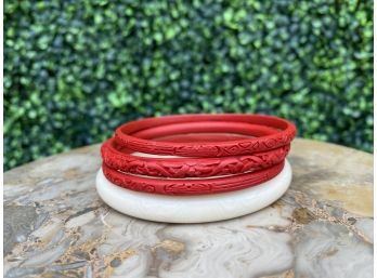 Three Narrow Carved Red Bangles And A Lucite White Bangle