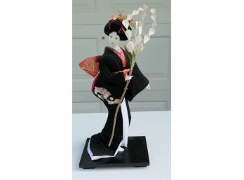 Vintage Geisha Girl Doll In Black Kimono With A Stem Of Flowers