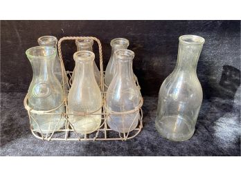 Seven Vintage Milk Bottles And A Wire Bottle Rack