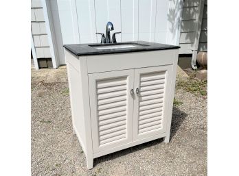 A Marble Top Vanity With Under Mount Sink And Louvered Doors