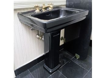 A Modern Black Pedestal Sink With Brass Fittings