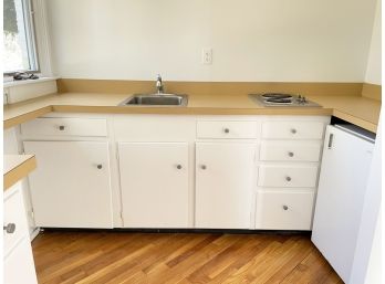 A Small Kitchenette With Sink And Electric Cooktop