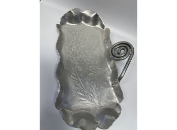 A Hand Wrought Metal Dish With Flower And Swirl Detail