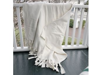 A Cream Polar Fleece Throw Blanket With Tied Fringe