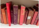 Three Shelves Of Hard Bound Books In Shades Of Red