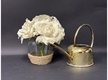 A Faux Rose Arrangement In A Glass & Rope Bowl With A Small Watering Can