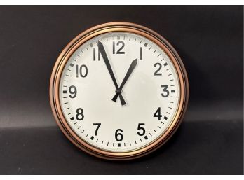 A Classic Wall Clock In A Coppery Metal Case
