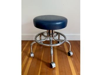 A Vintage Chrome Rolling Stool With Blue Vinyl Cushion