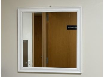 A Square Wall Mirror In A White Frame