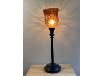 A Black Metal Lamp With Amber Toned Glass Shade