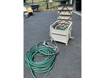 A Suncast Molded Plastic Hose Reel Box With Extra Hose And Sprinkler
