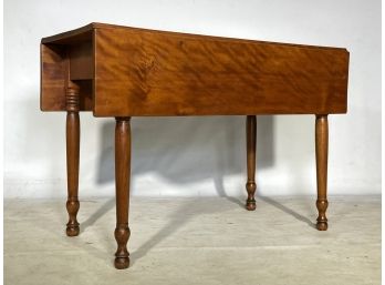 An Antique Tiger Maple Drop Leaf Table With Turned Legs
