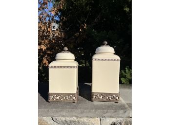 A Pair Of Ornate Lidded Ceramic Containers With Metal Embellishment