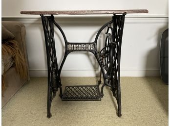 A CAST IRON SINGER SEWING MACHINE WITH A MARBLE TOP