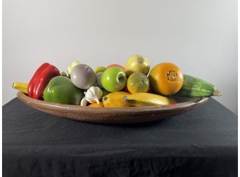 A LARGE FRENCH REDWARE TRENCHER FORM BOWL WITH WOODEN FRUIT