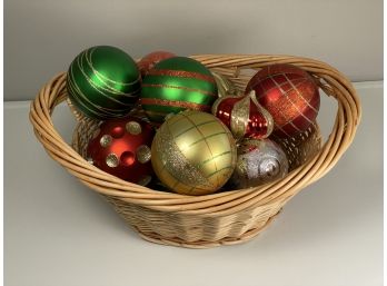 A Natural Woven Basket Full Of Oversized Plastic Christmas Ornaments