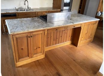 A Kitchen Island With Granite Counters, Paneled Pine Cabinetry, And Viking Cooktop