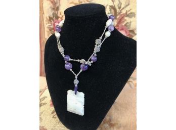 WHITE JADE AND AMETHYST ANTIQUE NECKLACE ON CORD. PENDENT MEASURES 2 INCHES X 1.5 INCHES.