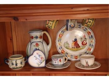 ASSORTED HENRIOT QUIMPER ART POTTERY DISHES INCLUDES WATER PITCHER, LARGE PLATE, CUPS & SAUCERS.