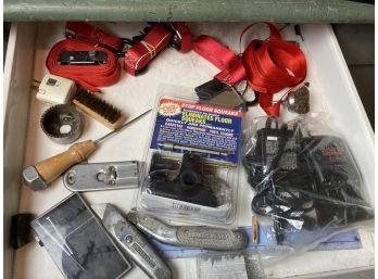 Drawer Of Assorted Tools Featuring Utility Knives, Straps, And Floor Squeak Eliminator Kit