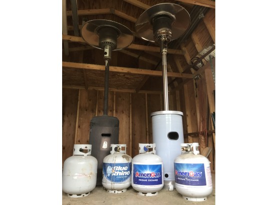 Two Tall Outdoor Propane Heaters With Two Full Propane Tanks And Two Empty Tanks