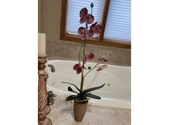 3 Bathroom Decorations Featuring Faux Orchid, Three Tall Candles, And A Large Wicker Basket
