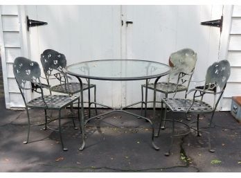 An Unusual Wrought Iron Patio Set Consisting Of A Round Glass Top Table And 4 Matching Chairs.