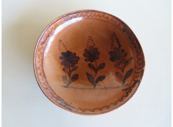 A Terracotta Plate Decorated With Hand Painted Flowers