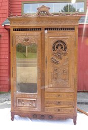 Elaborately Carved And Spool Turned Oak Armoire With Drawers And A Beveled Glass Mirror