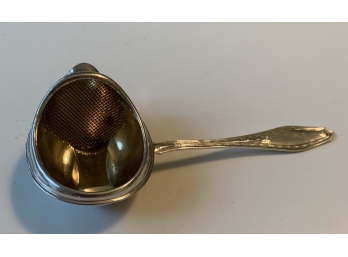 STERLING SILVER TEA STRAINER WITH GOLD WASH.