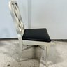 A Pair Of Infinity Back Chairs With Off White Frames And Black Seat Cushions