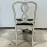 A Pair Of Infinity Back Chairs With Off White Frames And Black Seat Cushions