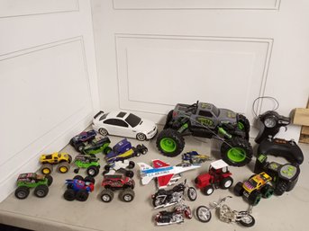 A Large Collection Of Toy Vehicles, Includes Monster Trucks And 3 Remote Controls