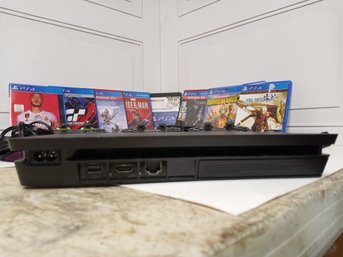 A PlayStation 4 Console System. Includes 3 Controllers, Connecting Cords, And 8 Games.