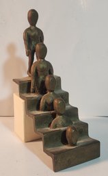 Bronze Sculpture Of Figure Desending Down A Staircase