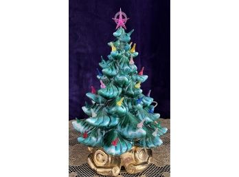 A Lighted Vintage Ceramic Christmas Tree On Music Box Stand