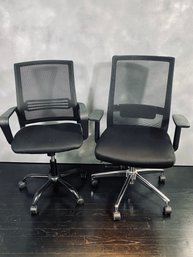 Pair Of Black Unmarked Desk Chairs On Wheels