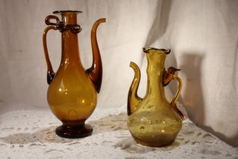 Hand Blown Amber Glass Pitchers With Applied Handles And Ornate Designs And Shapes